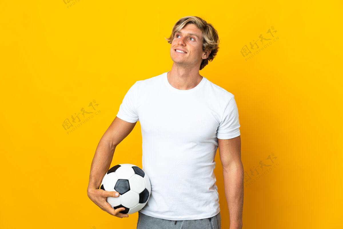 玩英国足球运动员在孤立的黄色背景下一边抬头一边思考着一个想法看解决方案肖像