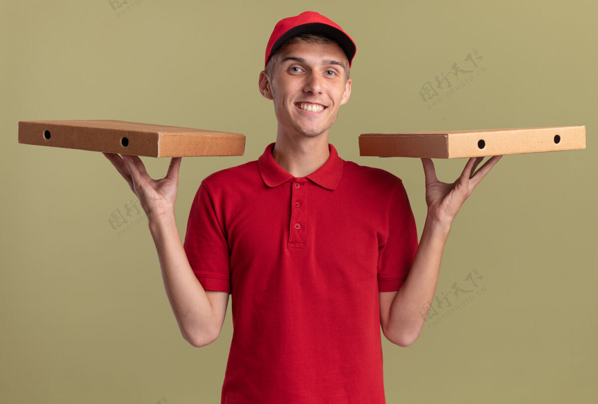 金发微笑的年轻金发送货员手上拿着比萨饼盒年轻绿色微笑