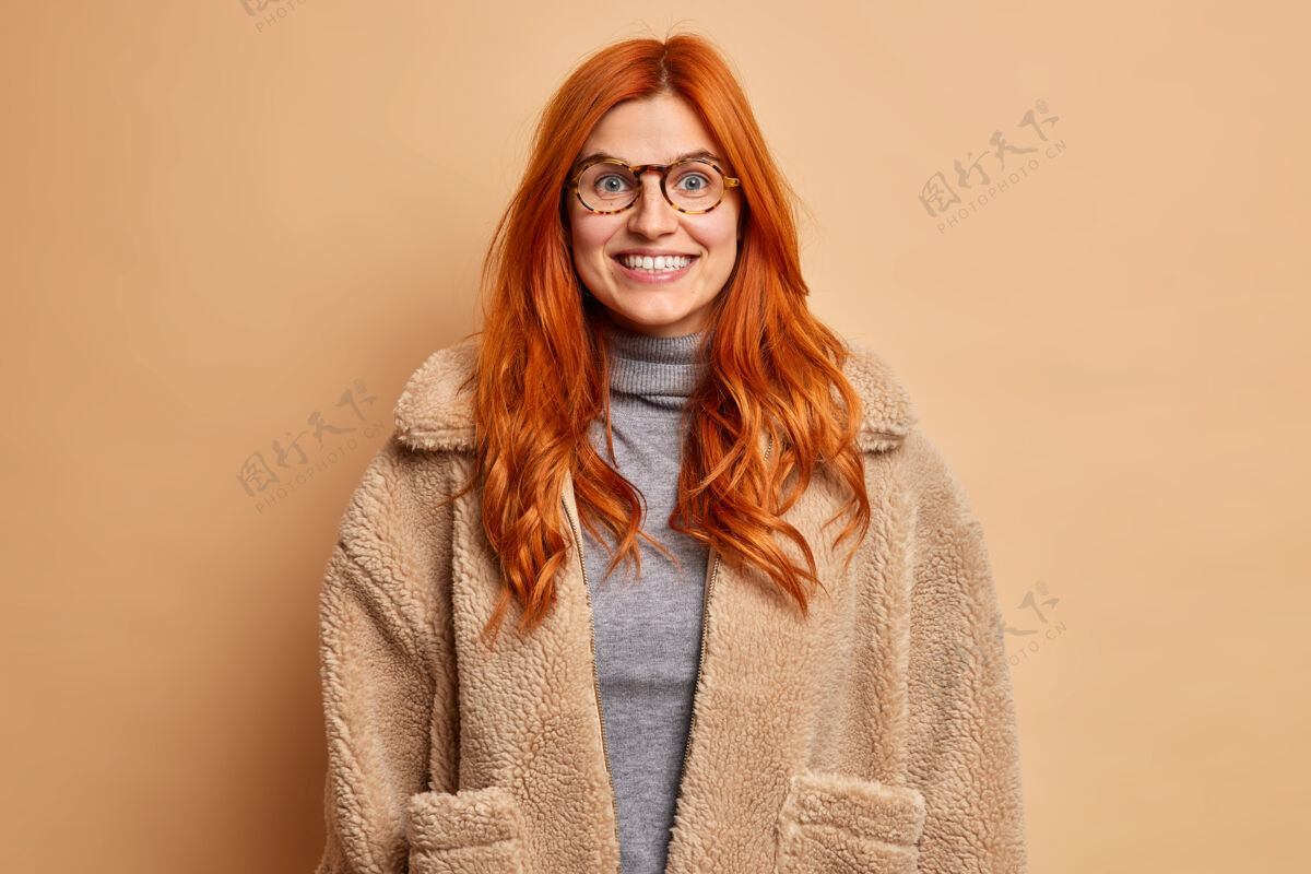 漂亮积极的红发女人穿着暖和的皮草外套微笑愉快有好心情表达快乐的情绪肖像女人欢呼