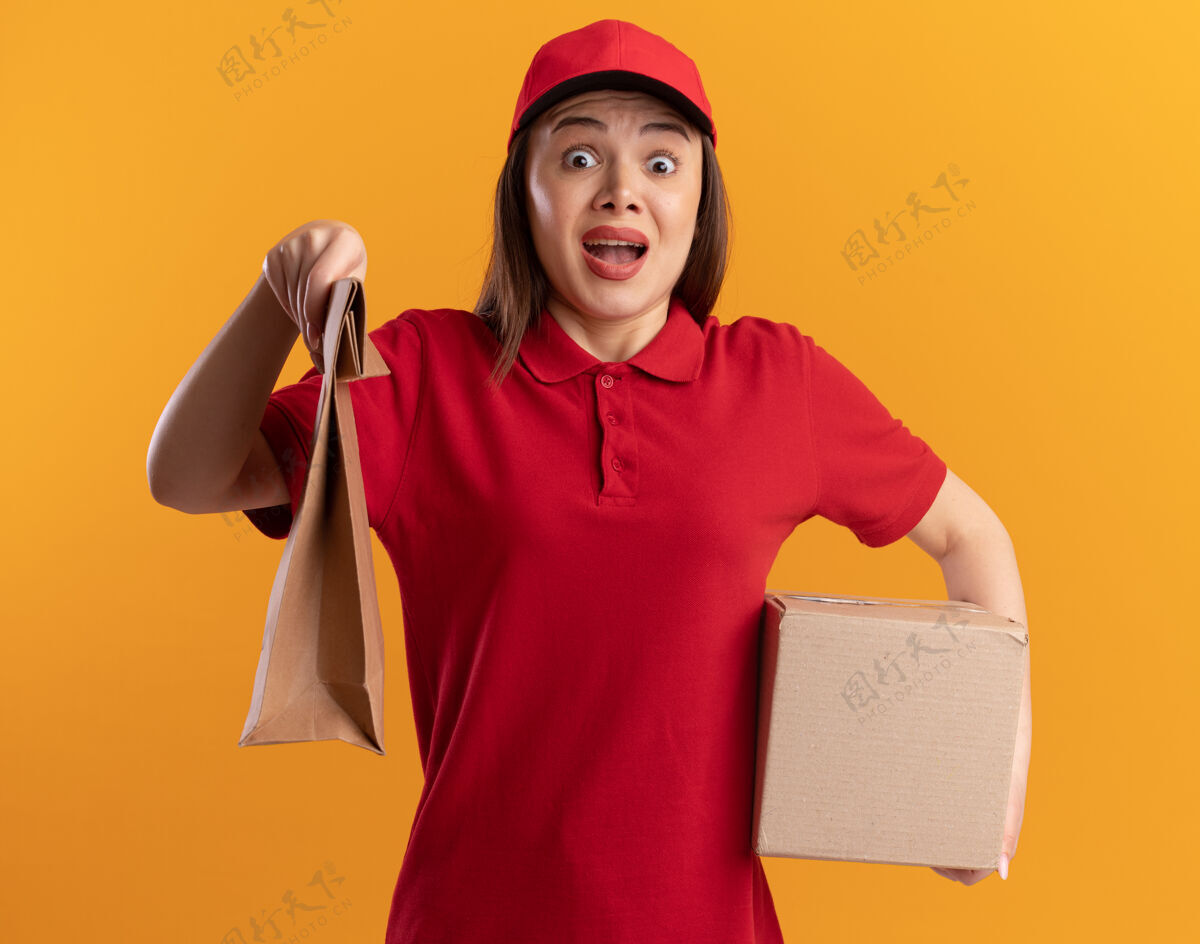 漂亮穿着制服的焦急漂亮的女送货员手里拿着橘黄色的纸包和名片盒包装制服焦虑