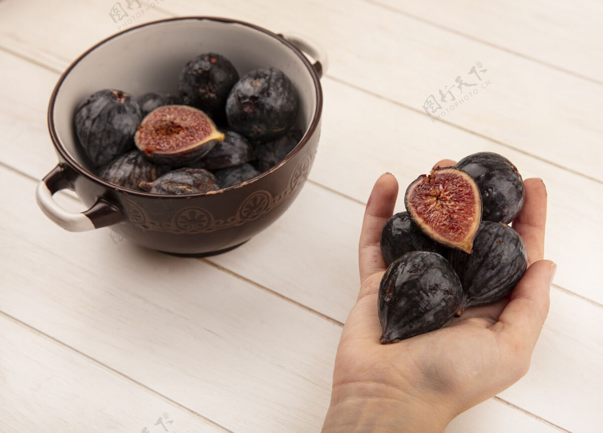 水果顶视图的女性手拿着甜蜜的黑色任务无花果在白色的木制表面健康饮食手