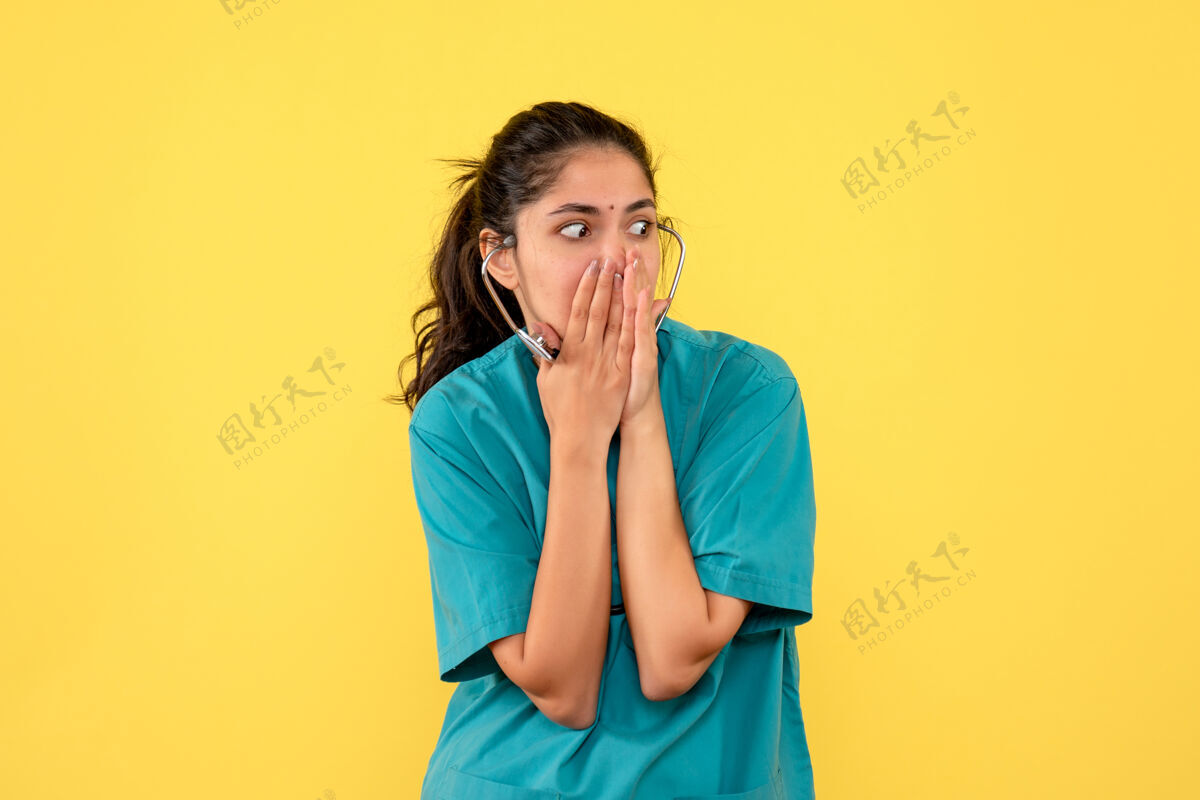 惊人前视图穿着制服的女医生双手放在黄色背景的脸上肖像商业人物