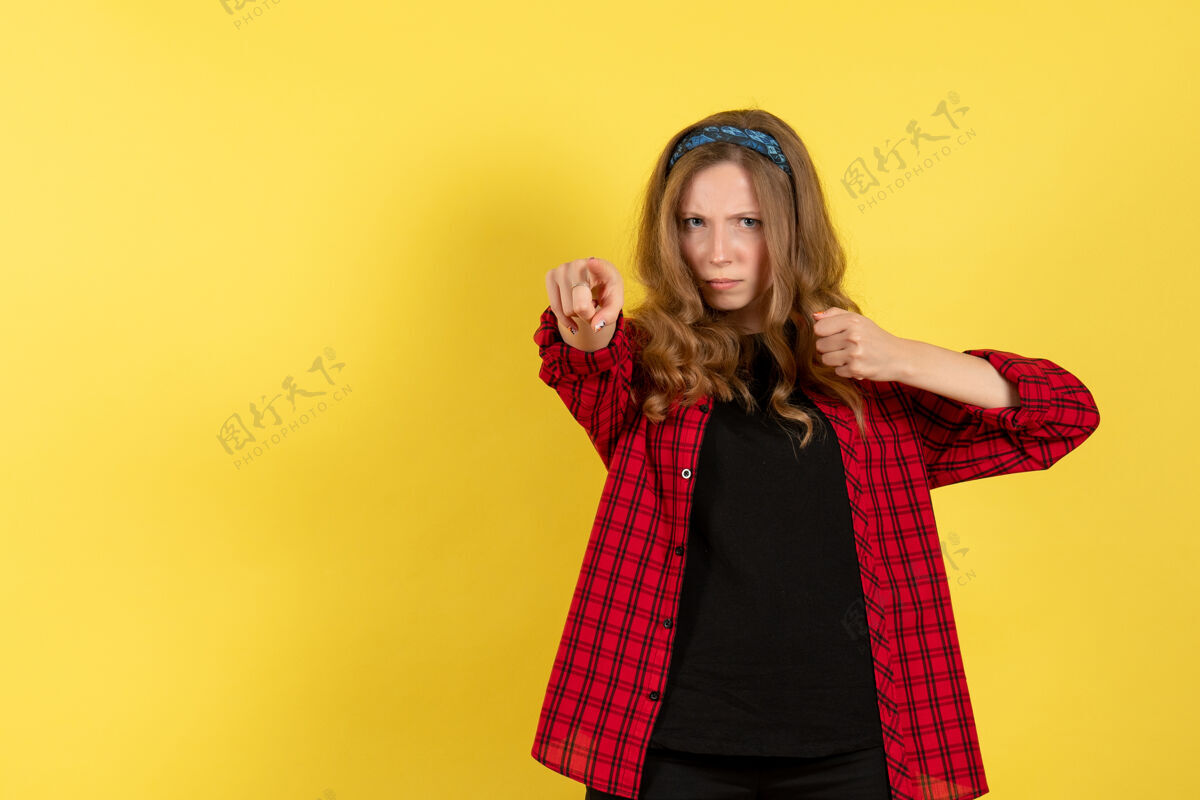 情感正面图身着红色格子衬衫的年轻女性站在黄色背景上摆姿势模特女孩人类女性色彩情感站着成人肖像