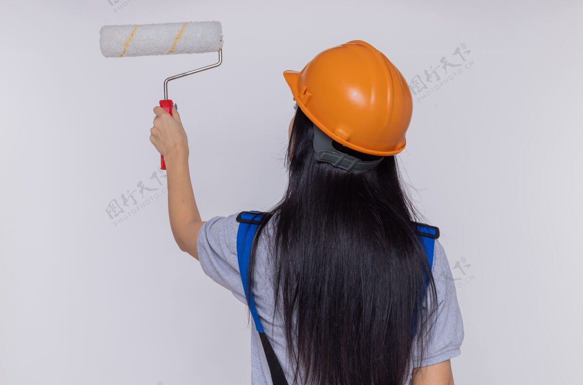 头盔身穿施工制服 头戴安全帽的年轻建筑工人油漆墙壁安全