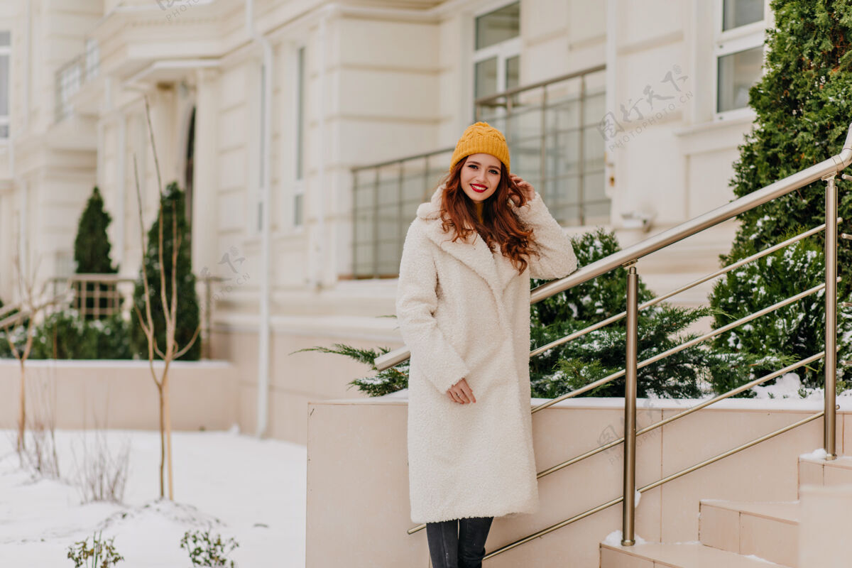 寒冷美丽的白人女孩在户外度过冬季周末可爱的姜黄色女人在白色外套摆姿势女孩城市季节