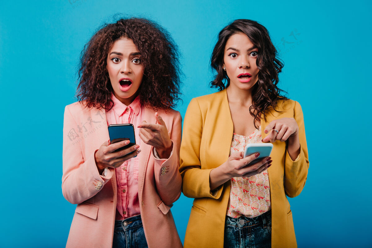社交两个黑发女人拿着智能手机信息手机交流