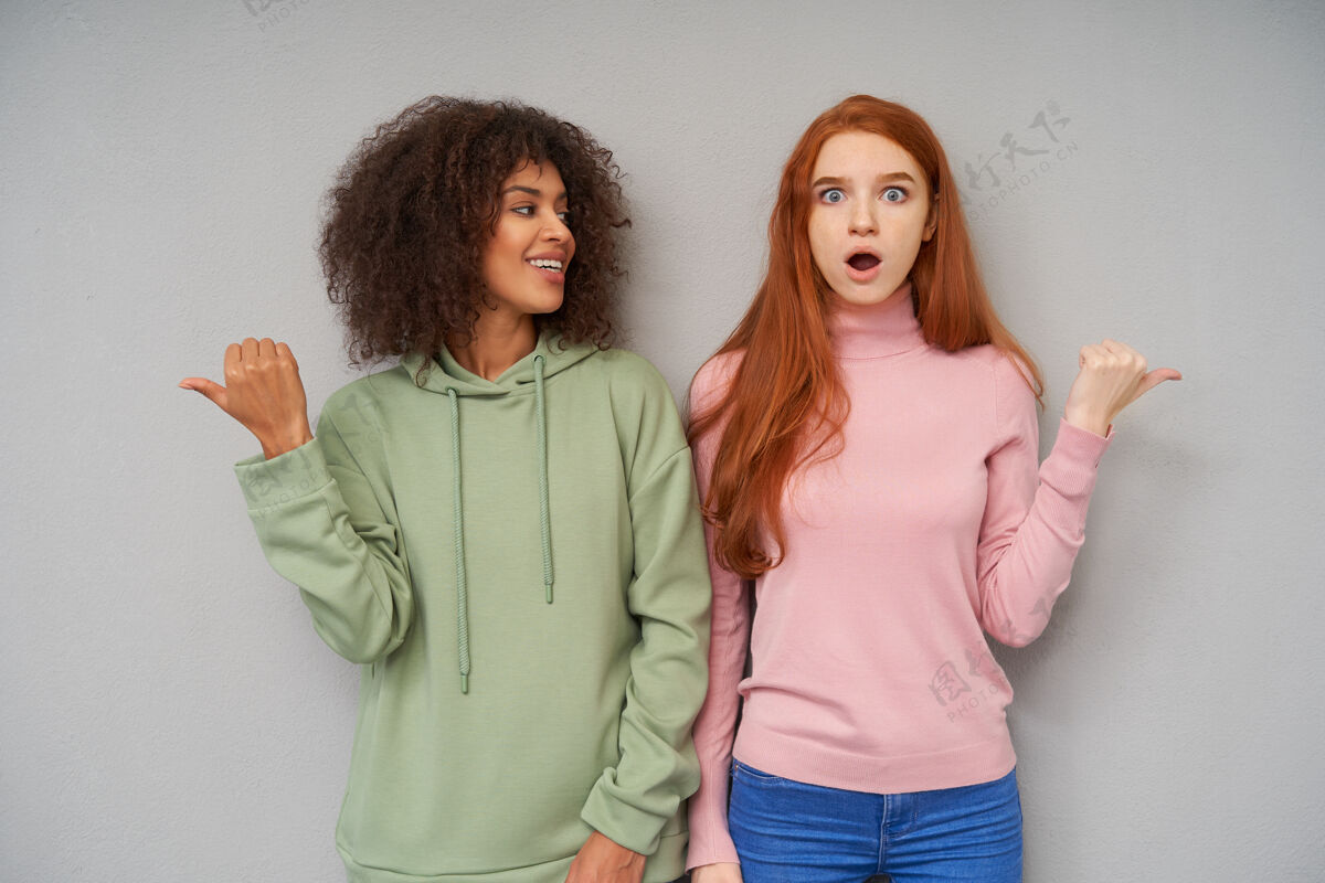 情感室内镜头：漂亮的年轻女子站在灰色的墙壁上 用手指着不同的方向 展现出不同的情感立场提高模型
