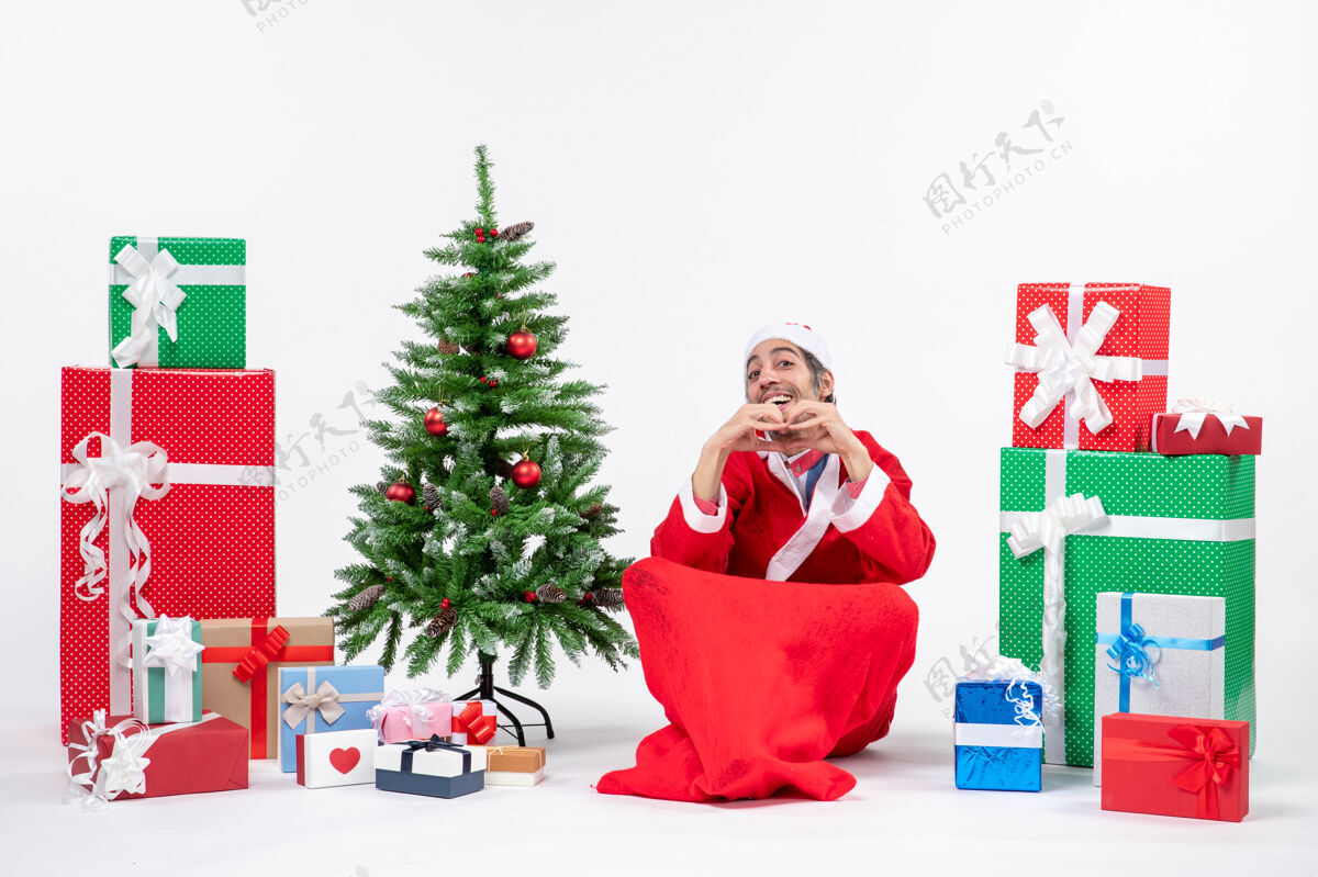 盒子有趣的年轻人庆祝新年或圣诞节假期坐在地上附近的礼物和装饰圣诞树礼物男人装饰