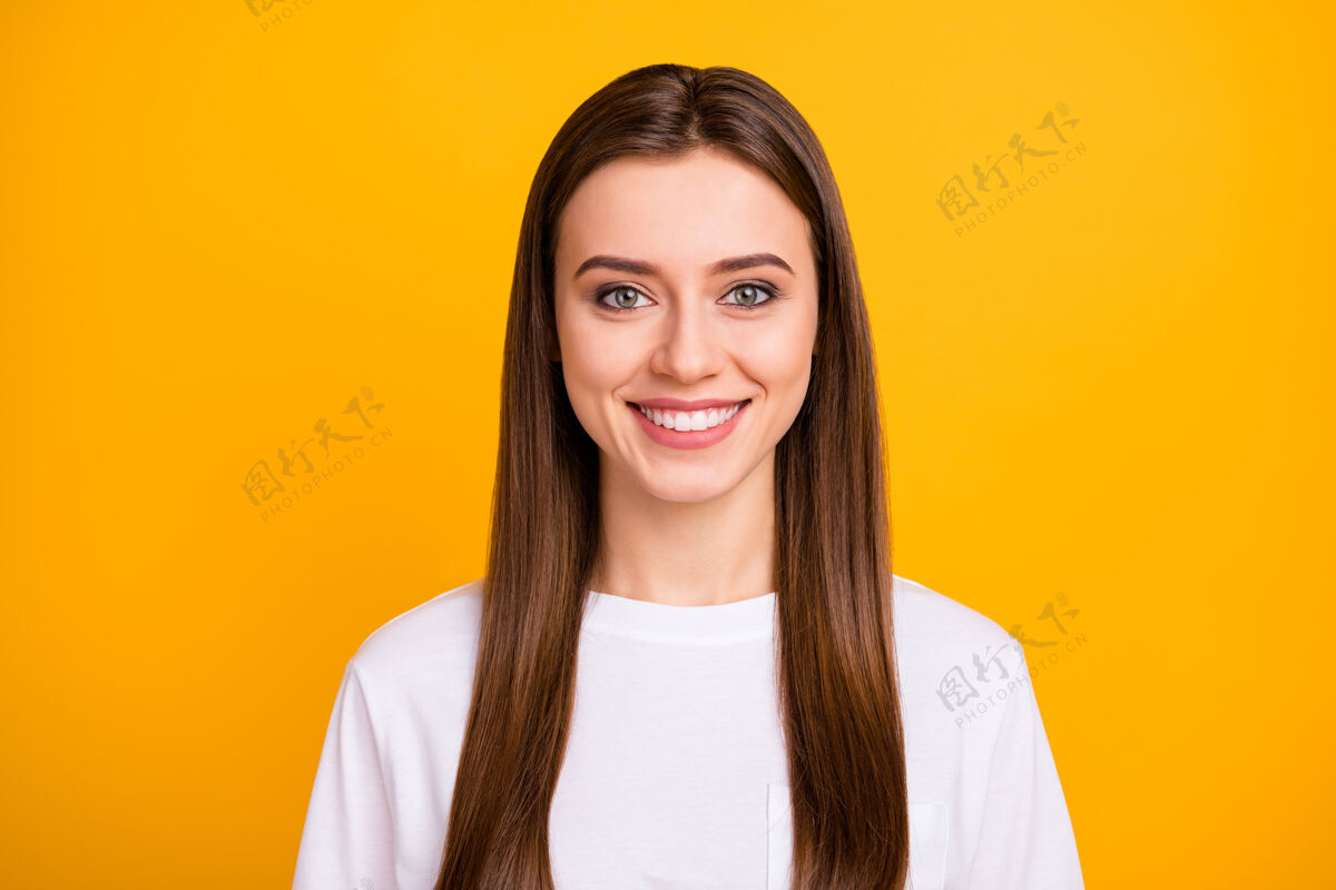 微笑可爱迷人开朗女士的特写照片心情愉快微笑修长完美的发型穿着休闲白色t恤隔离鲜艳的黄色墙壁黑发女性明亮