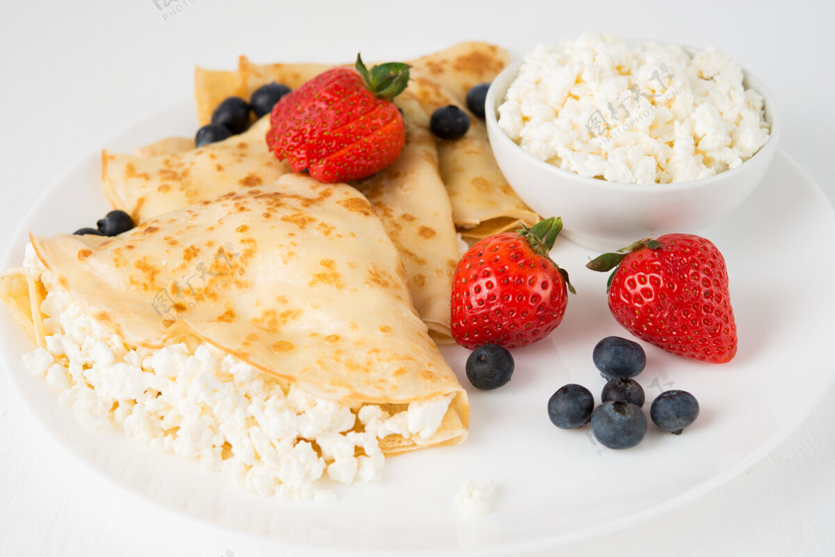新鲜传统的俄罗斯薄饼与白干酪和浆果在一个盘子里 特写餐桌水果金色