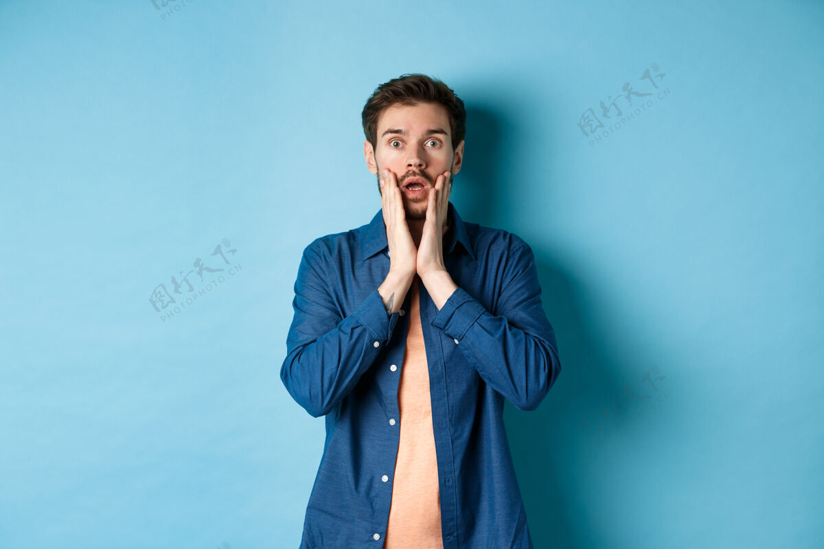 站立这张照片是一个男人喘息着 下巴耷拉着 脸上带着震惊的表情 吃惊地盯着镜头 站在蓝色的背景上肖像手成人