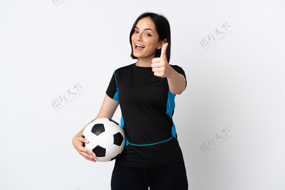 运动一个年轻的足球运动员 一个被隔离在白色背景下竖起大拇指的女人 因为发生了好事手指站立运动员