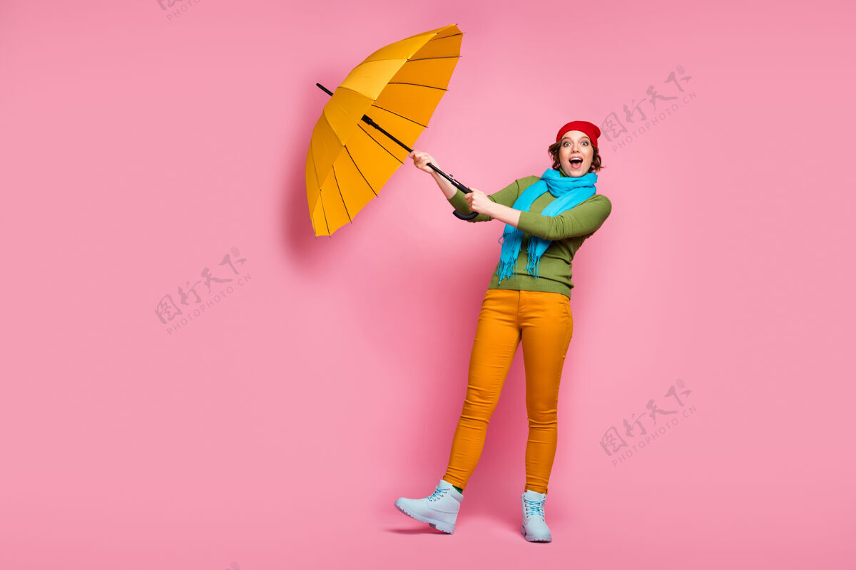 伞全身照片兴奋的女孩旅行旅行她的阳光伞飞行风空气她尝试捕捉尖叫哇omg穿蓝红色头饰套头衫冬季裤子隔离粉红色墙壁帽子风下雨
