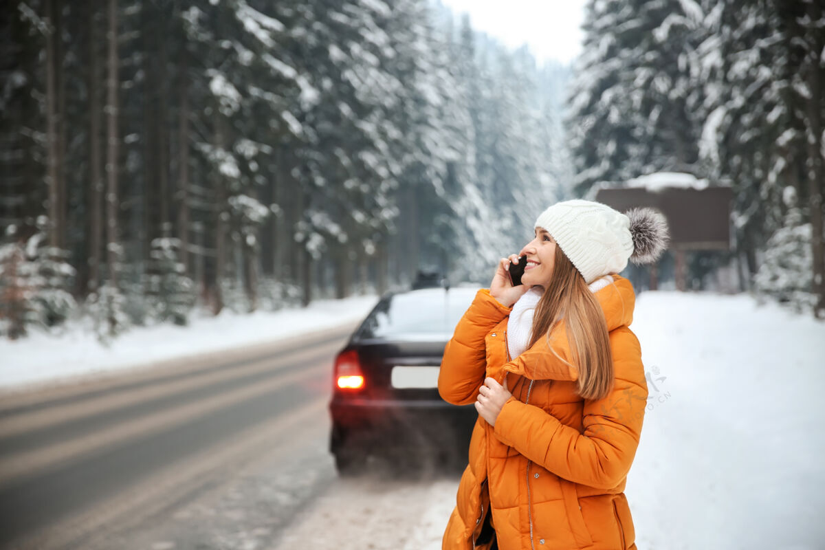 天气在冬季度假胜地 一个年轻的女人在马路边打电话人自然雪