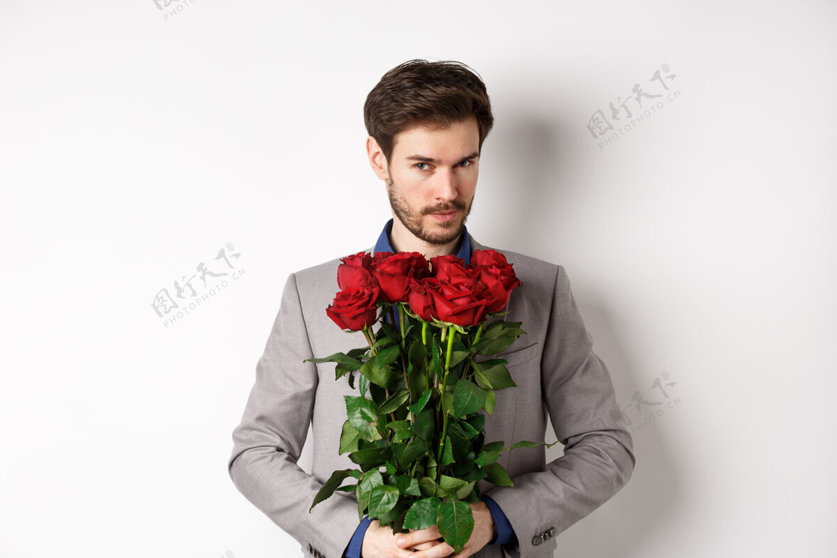 惊喜帅哥穿西装去约会 捧着一束红玫瑰对着镜头微笑 做情人节惊喜礼物 白色背景男朋友情感花