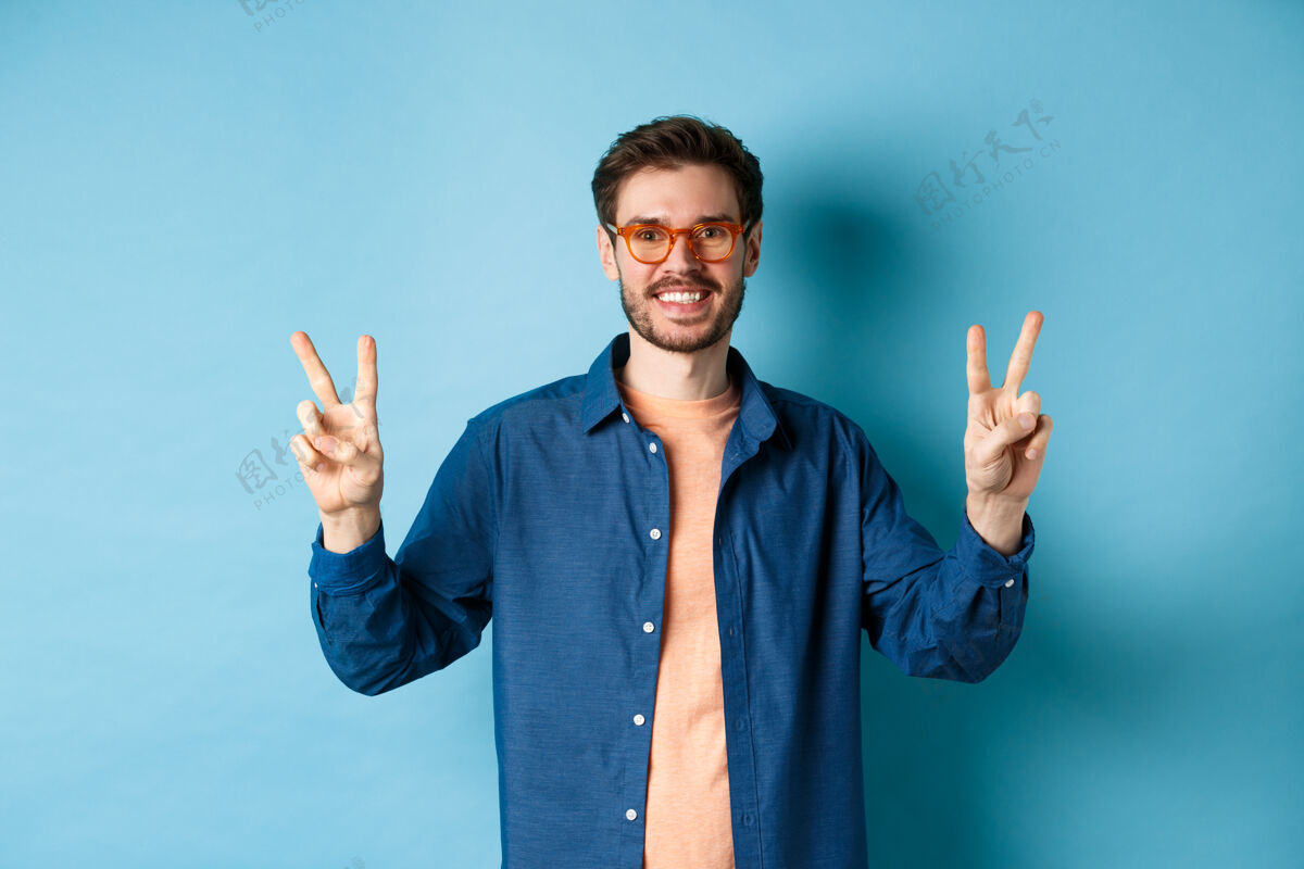 男性开朗的家伙摆出和平标志在新眼镜 眼镜店推广的概念时尚站商店