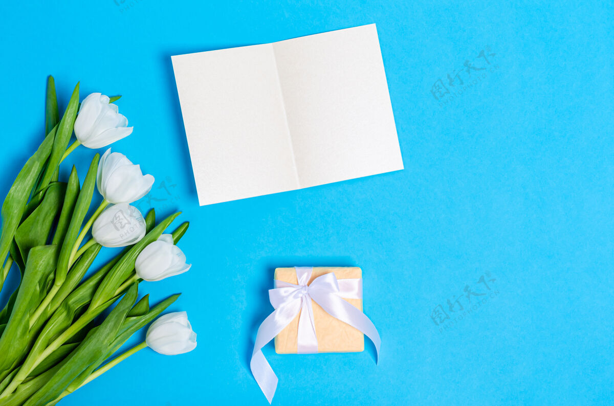 丝带一束白色郁金香 一张贺卡和一个浅蓝色的礼盒空白花束平铺