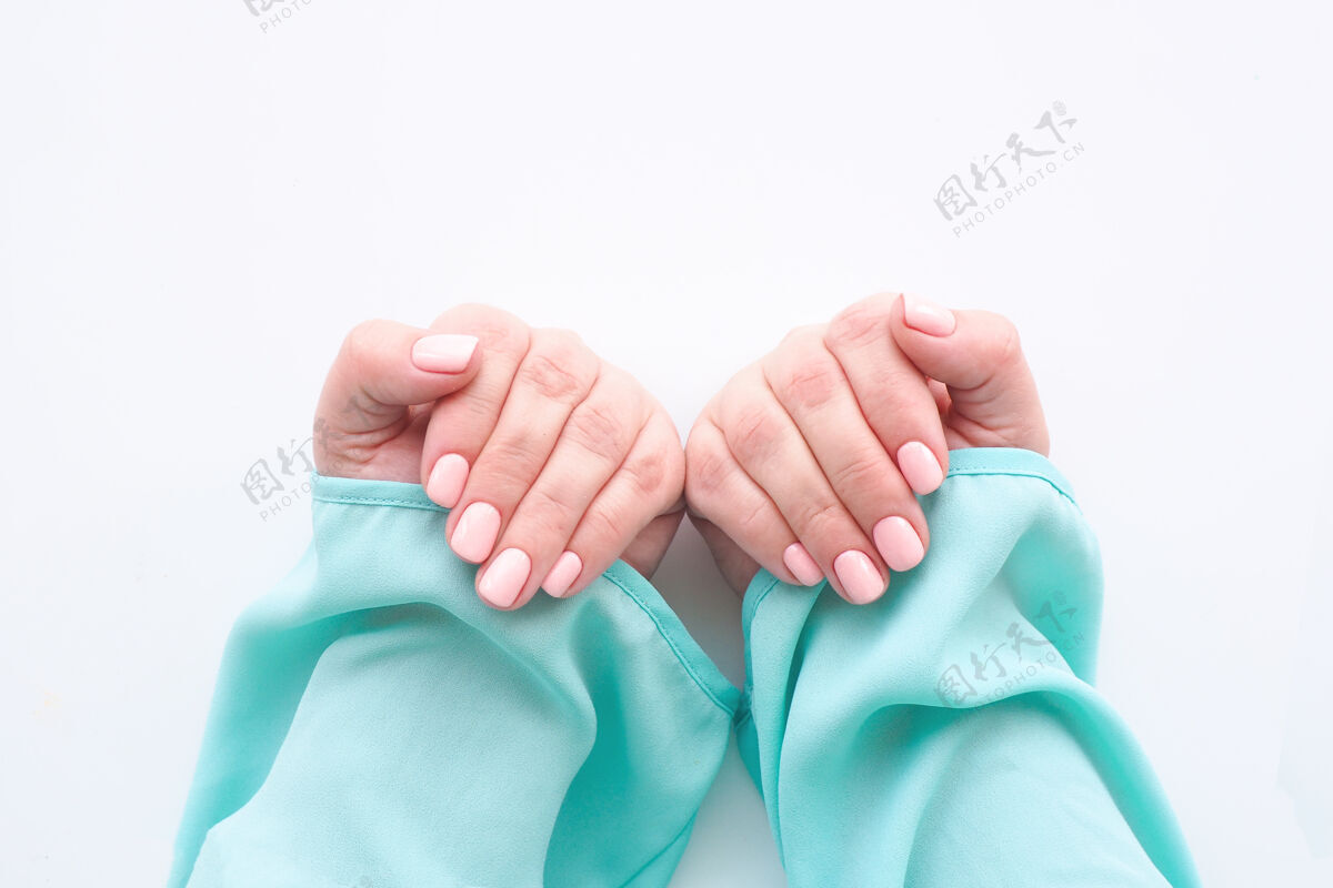 修指甲女性手在一个美丽的指甲和白色软粉红色指甲油蓝色上衣女衬衫手指