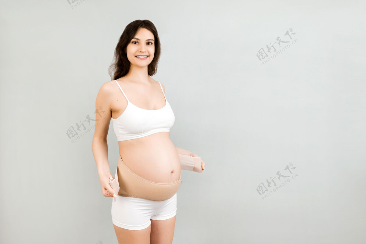 母亲穿内衣的孕妇戴上绷带腹部妇女绷带