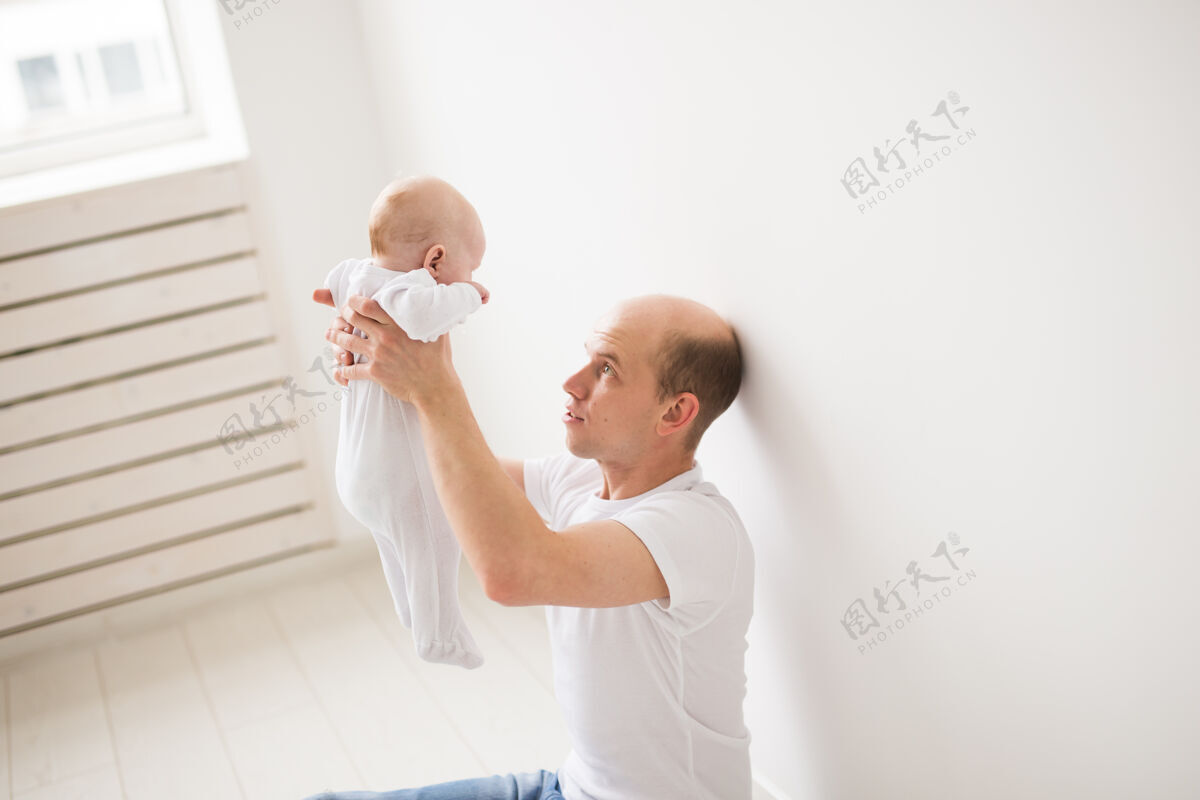 年份孩子 家庭和父亲的概念-快乐的秃头父亲抱着小女儿在白色的房间30岁沙发生活