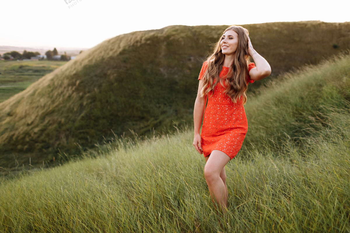 草地田野上绿草丛中的红衣美女画像女孩春天快乐