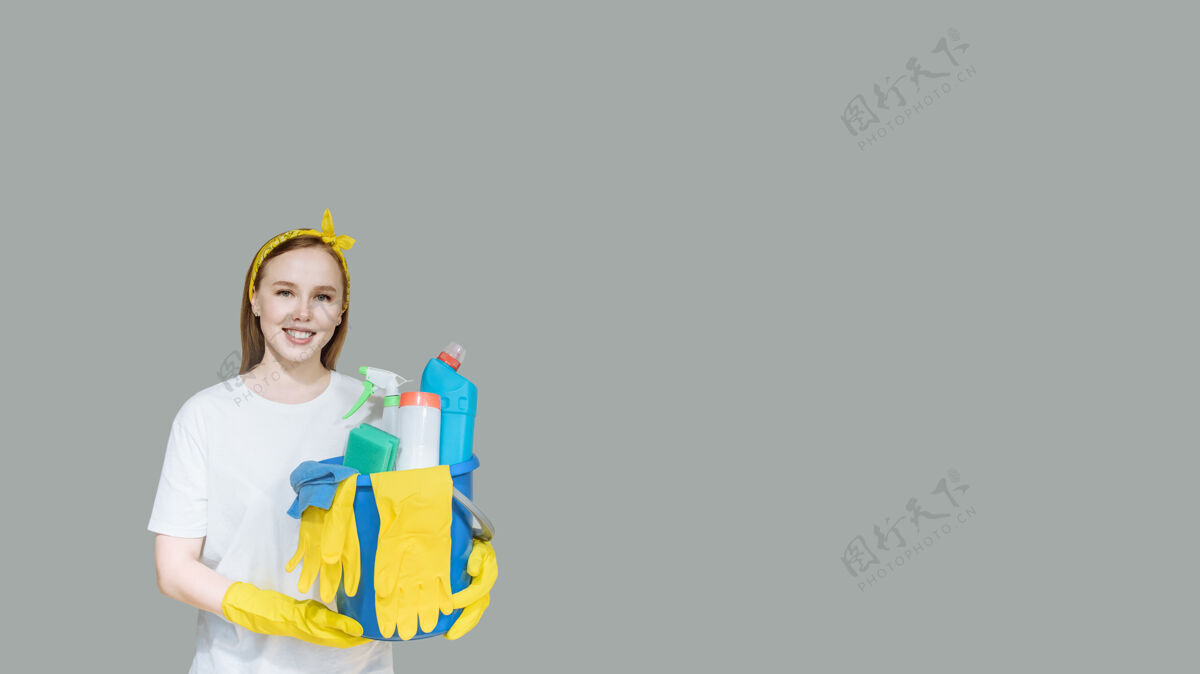 橡皮年轻的微笑女孩与家庭清洁用品上灰色的女佣复制空间女人手套