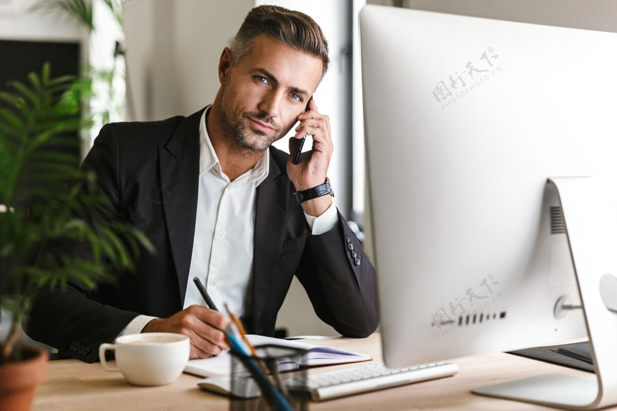 成功图为30多岁的成年商人穿着西装在办公室里用电脑打电话公司经理男士