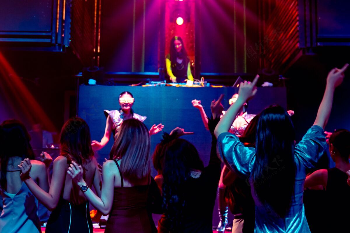 乐趣一群人随着舞台上dj的音乐节拍在迪斯科夜总会跳舞青年俱乐部女孩