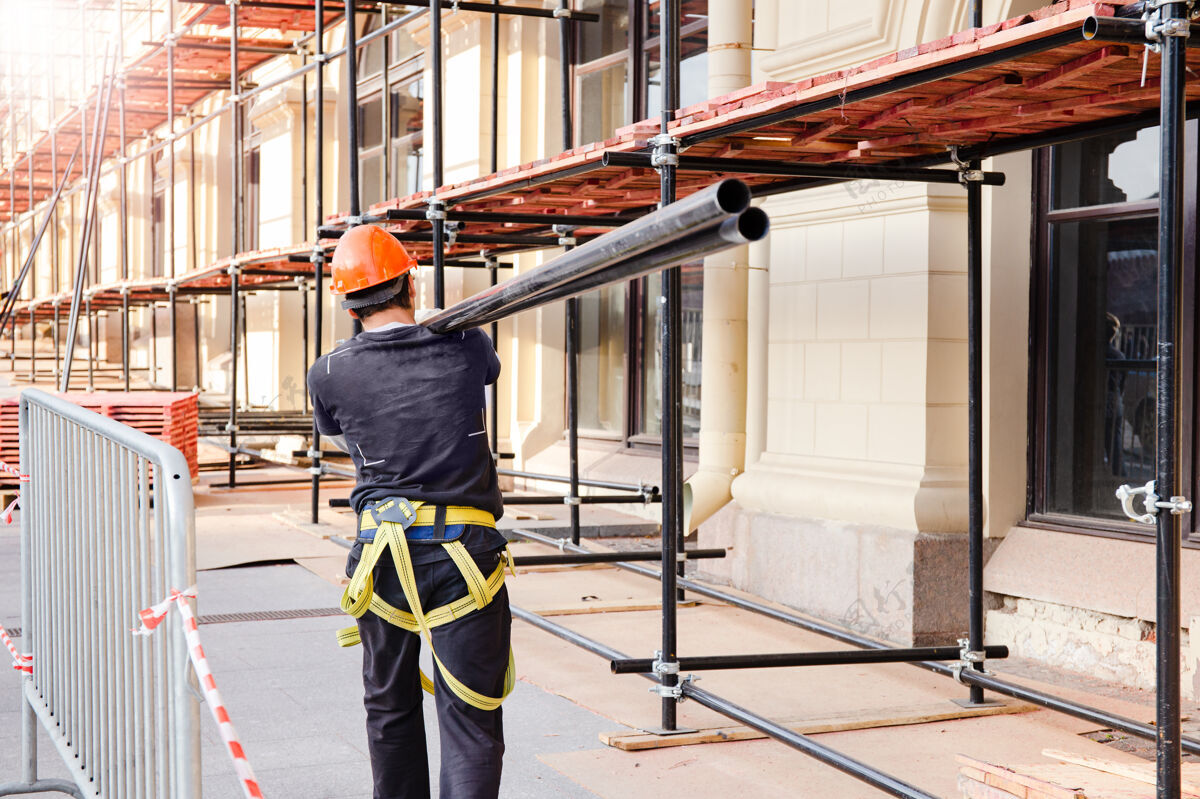 柱建筑工人肩上扛着一根钢梁施工现场 建筑施工及改造过程Diy结构钢筋