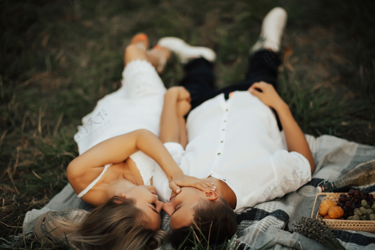 乡村在公园浪漫野餐时 躺在绿草上 美丽的女孩抚摸着男孩的脸女孩有机可爱