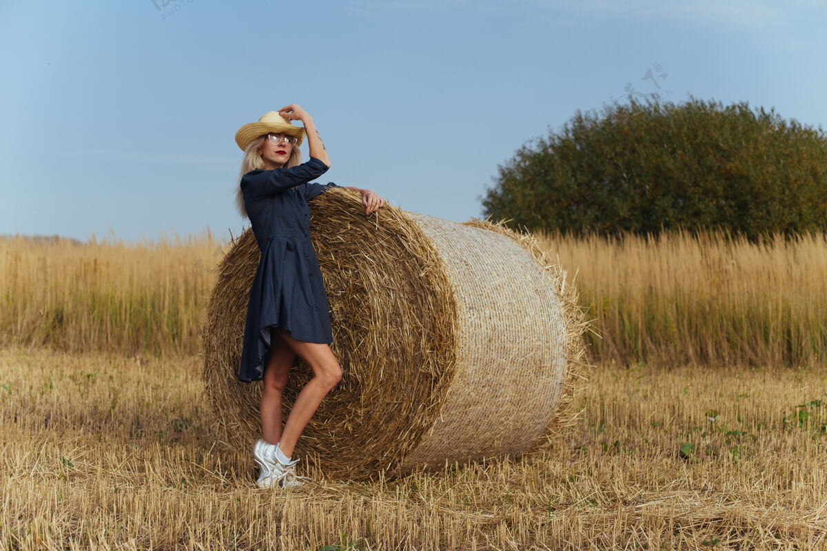 姿势一位年轻漂亮的女村民在一捆干草旁摆出一身衣服玻璃帽子稻草