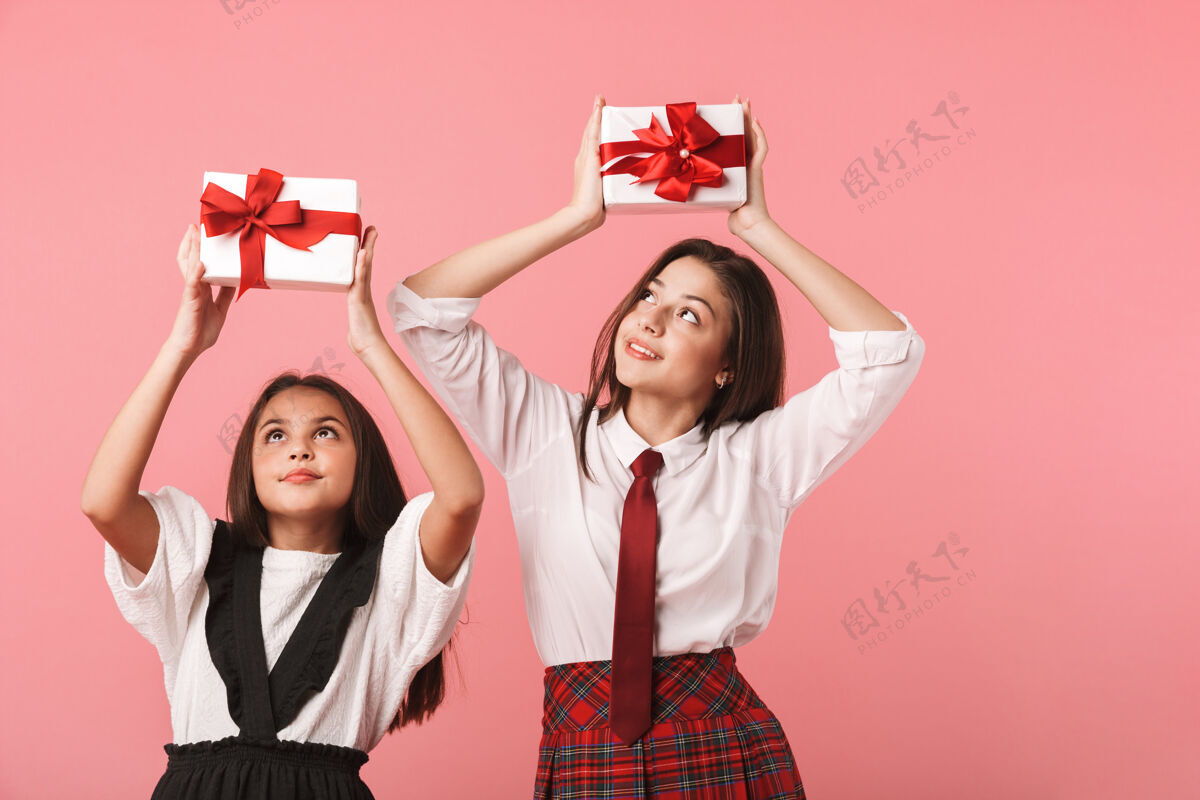 积极身着校服 手持礼品盒 与世隔绝地站在红墙上的快乐女孩的画像青少年年轻快乐