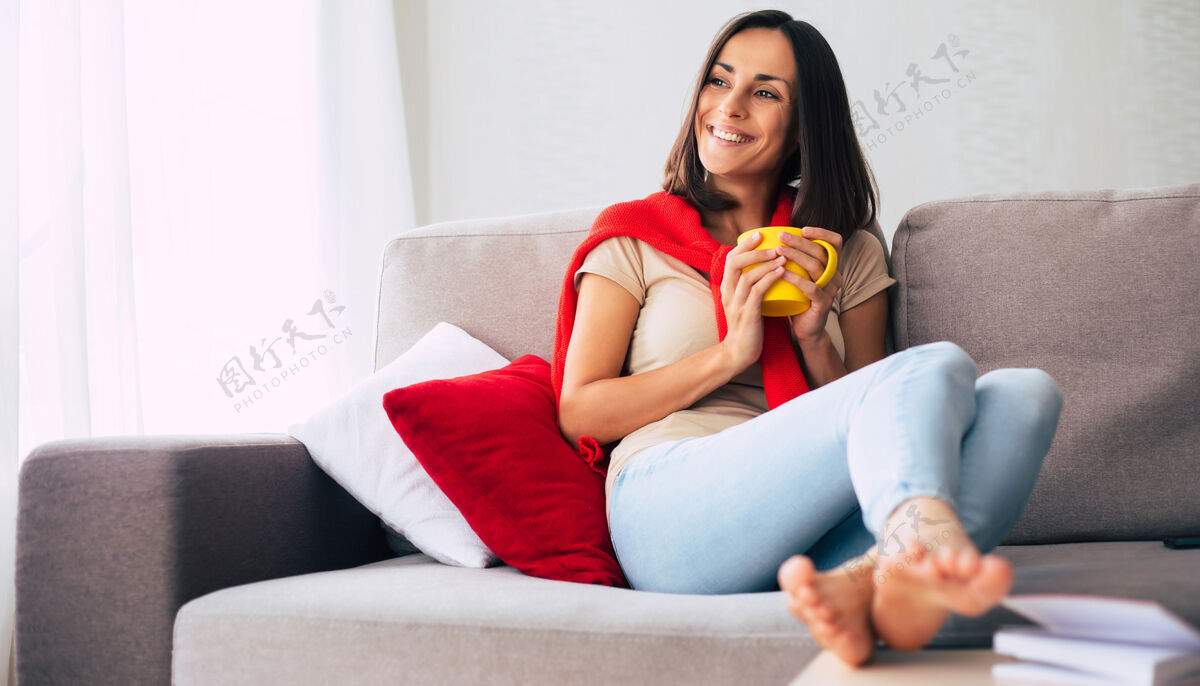 假日美丽的年轻快乐的黑发女人正在家里的沙发上放松和做梦女性喝酒休息