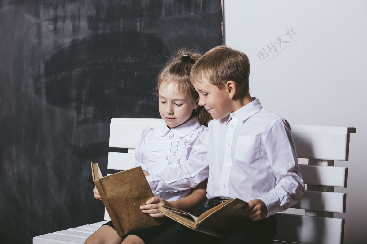 粉笔快乐的男孩和女孩从小学班的板凳上看书的背景板教育班级学生