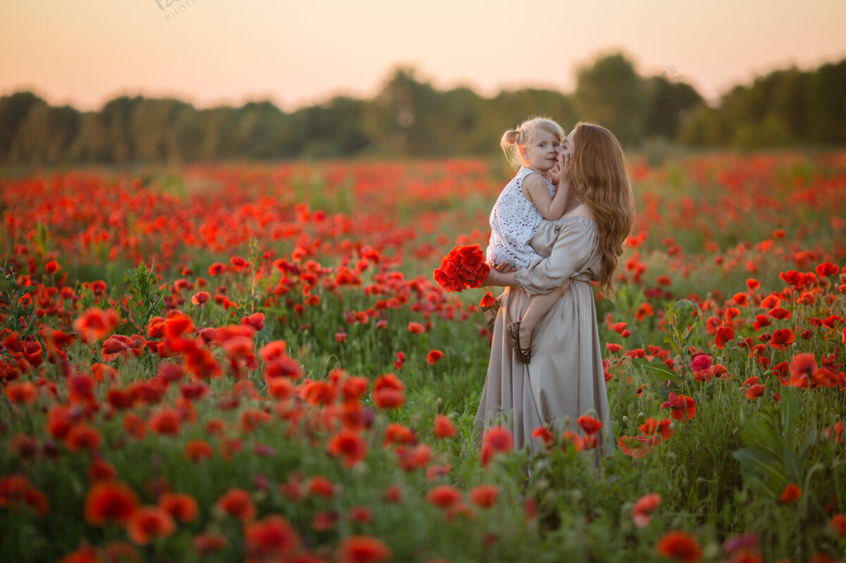 Holding夏天 妈妈在罂粟地里拥抱她的女儿PoppySummerField