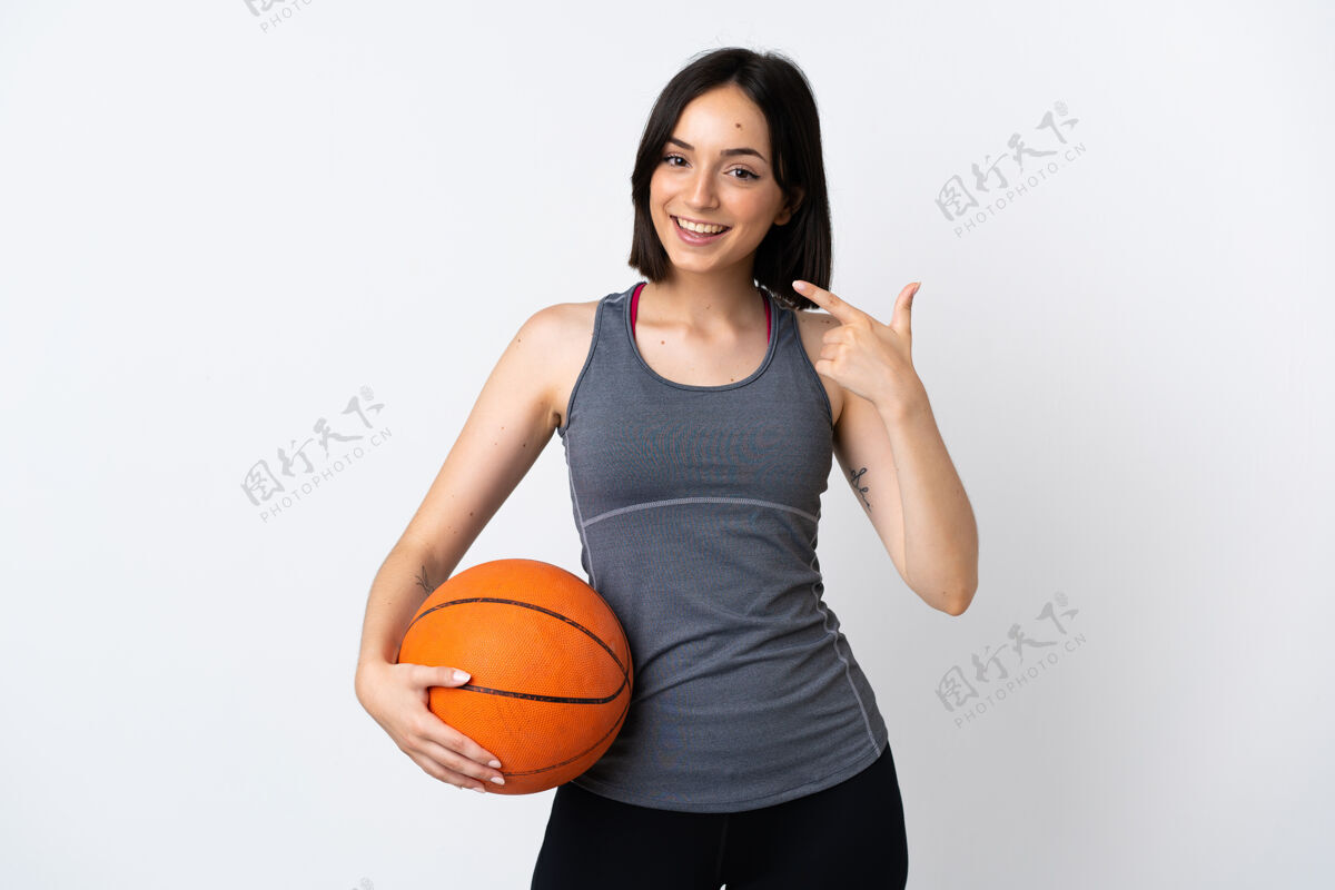 微笑在白墙上打篮球的年轻女子孤零零地竖起大拇指站立人运动