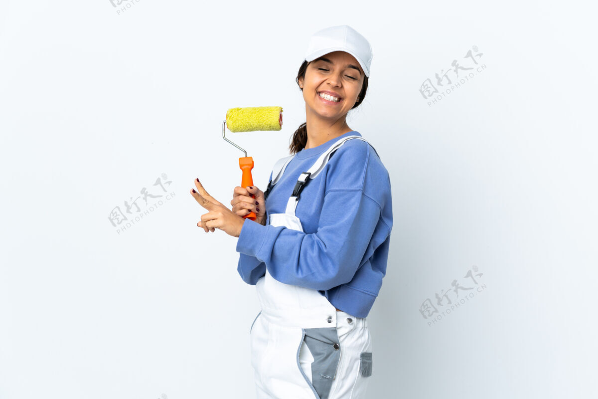 空白一位女画家在孤零零的白墙上微笑着 展示着胜利的标志改进乐趣胜利