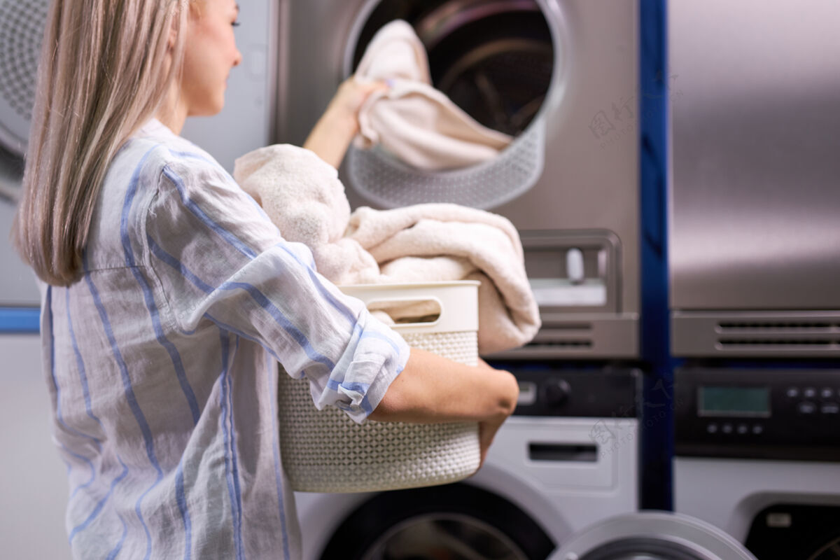 家庭家务：女人把衣服装进洗衣机机器高加索人这位女士喜欢打扫卫生过程.焦点在篮子里的毛巾上洗衣机洗涤剂杂务