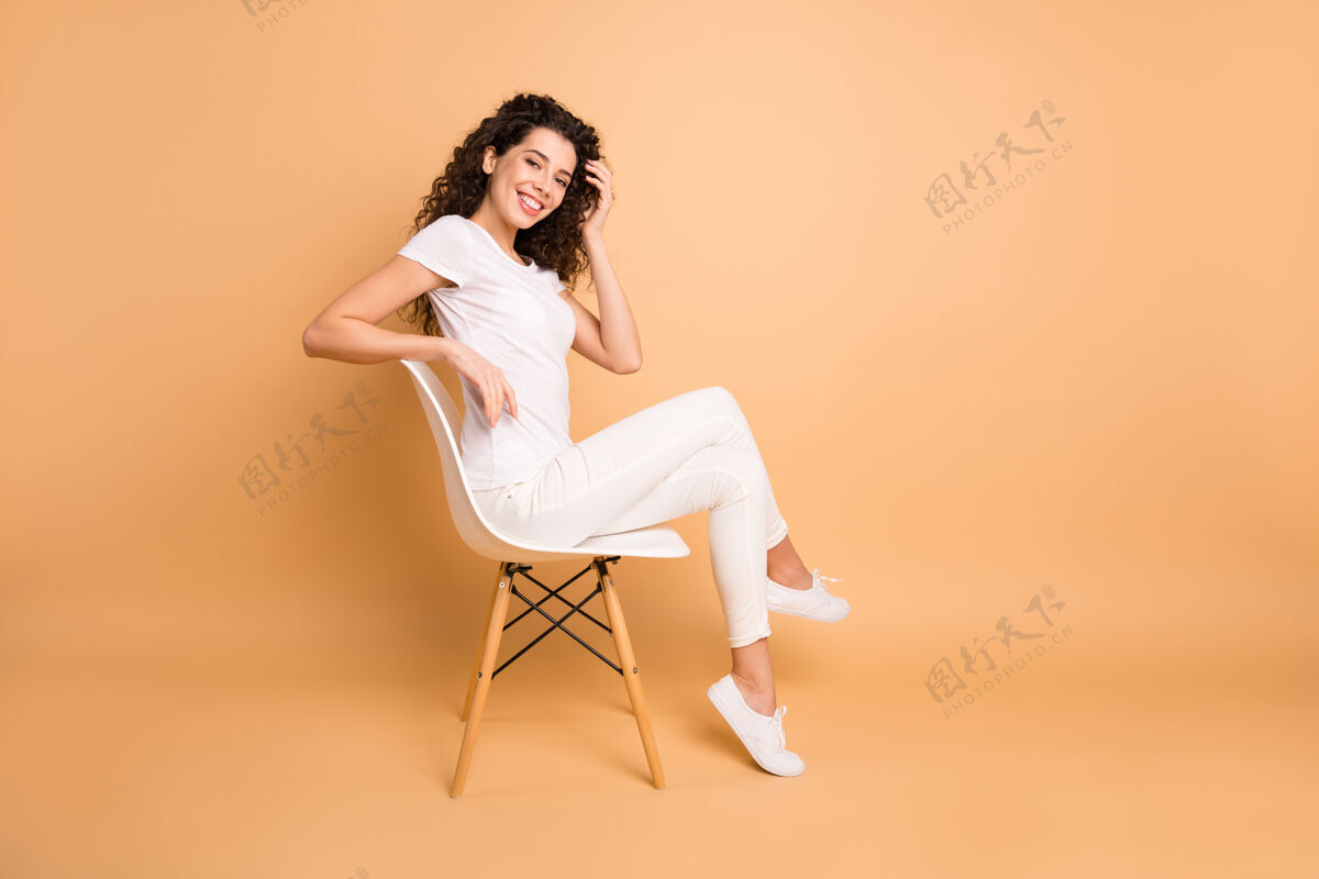 Swoosh全尺寸资料照片惊人的商务女士坐在舒适的椅子上微笑积极苗条的形状穿着休闲服隔离米色粉彩的颜色背景自信女性牙齿