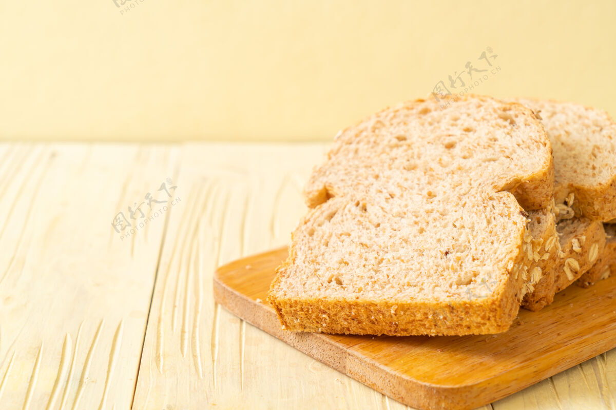 烘焙木桌上的全麦面包片面包屑种子面包