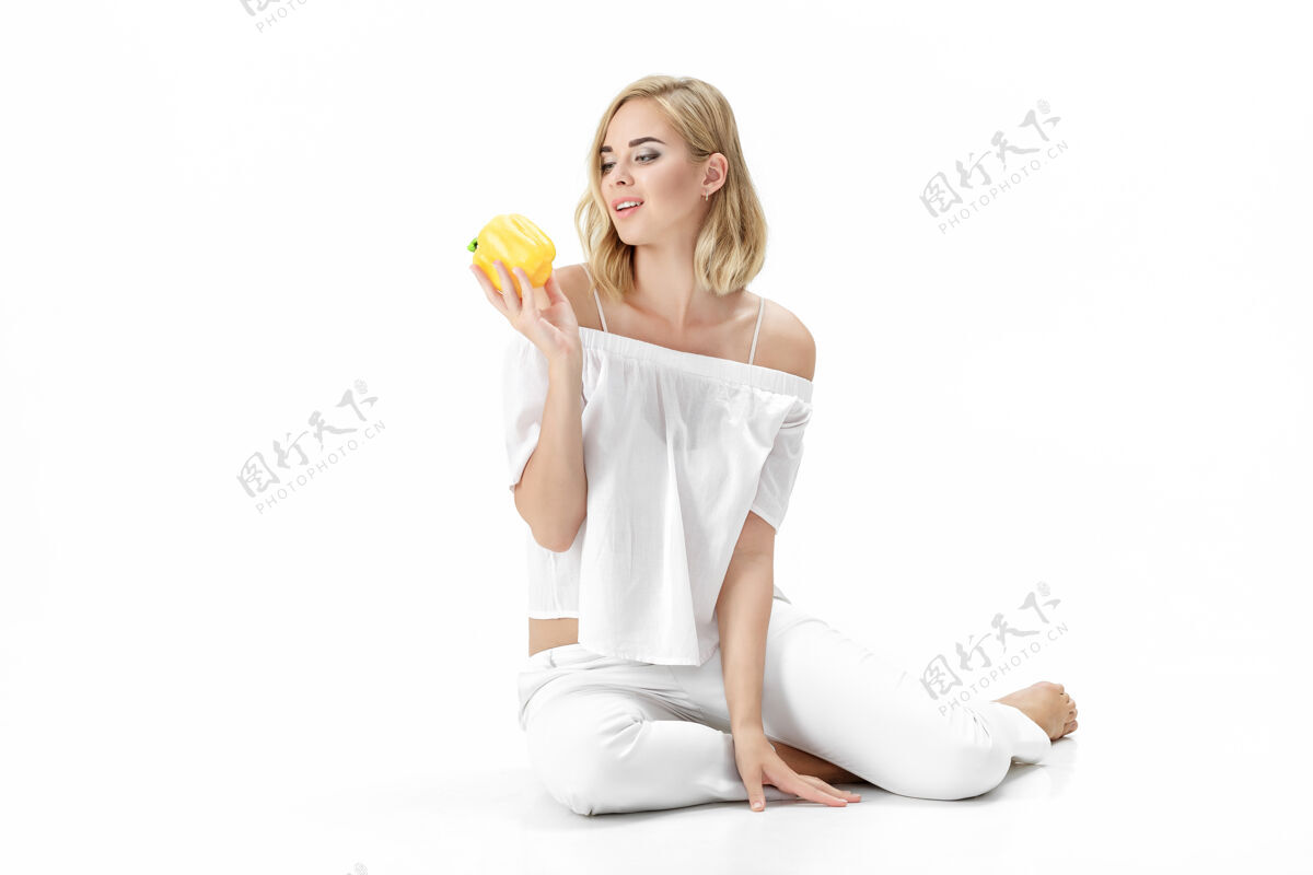 微笑美丽的金发女人穿着白色上衣拿着黄色的铃铛胡椒粉健康节食和节食有机蔬菜性感