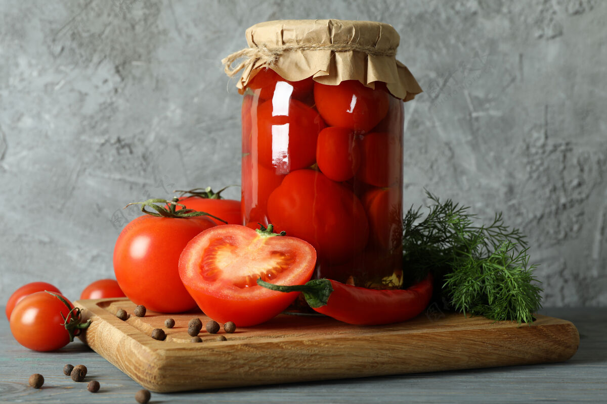 西红柿木板上放着一罐腌番茄灰色胡椒红色