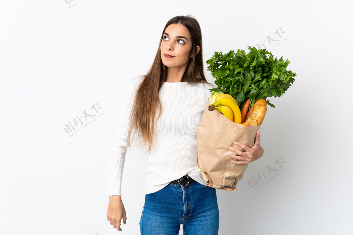 沉思年轻的白人妇女买一些食物孤立在白色背景思考一个想法 而抬头看奇迹解决方案健康