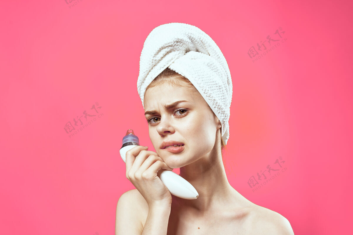 诊所漂亮的女人头上拿着毛巾手上拿着按摩器美容洁肤粉墙女性治疗病人