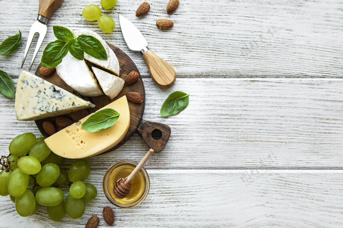 蜂蜜在一张白色的旧木桌上放着不同种类的奶酪和零食产品膳食配料