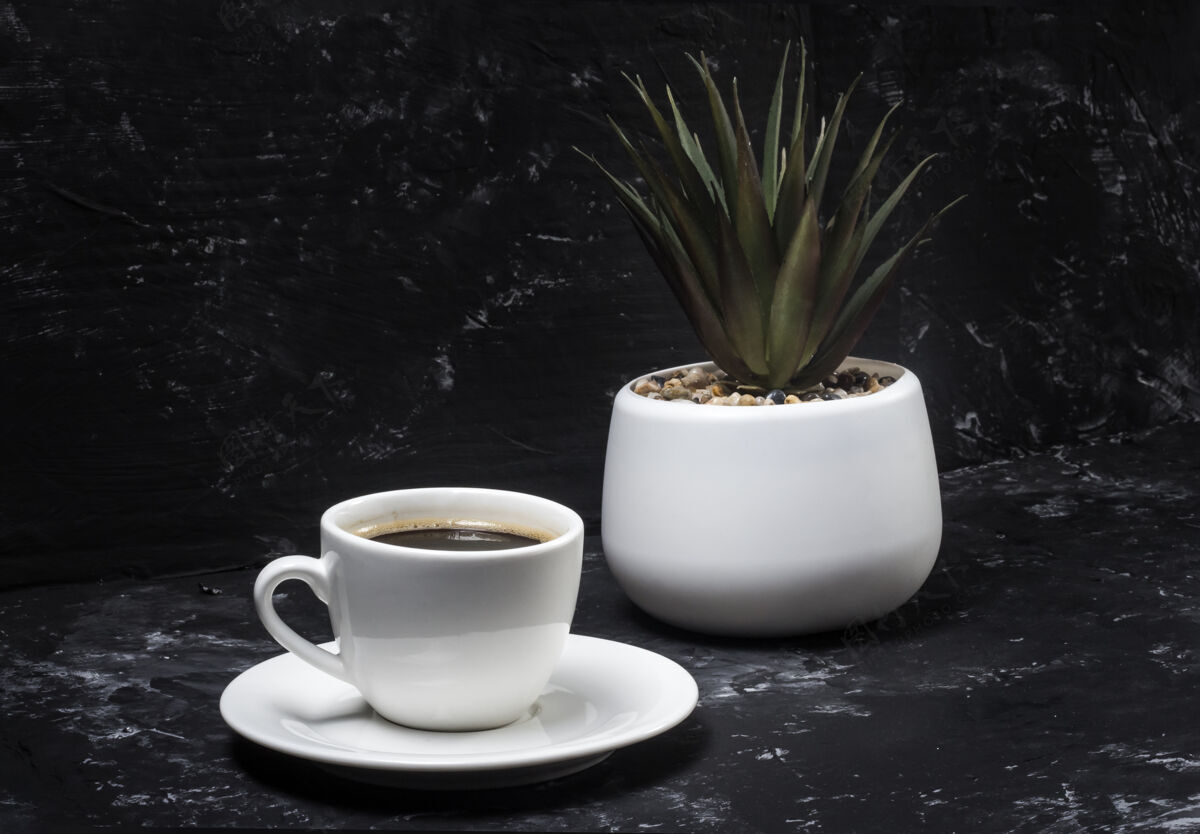 非酒精白色杯子 黑色抽象背景上有黑色芳香的咖啡 背景是盆花生活浓缩咖啡早餐
