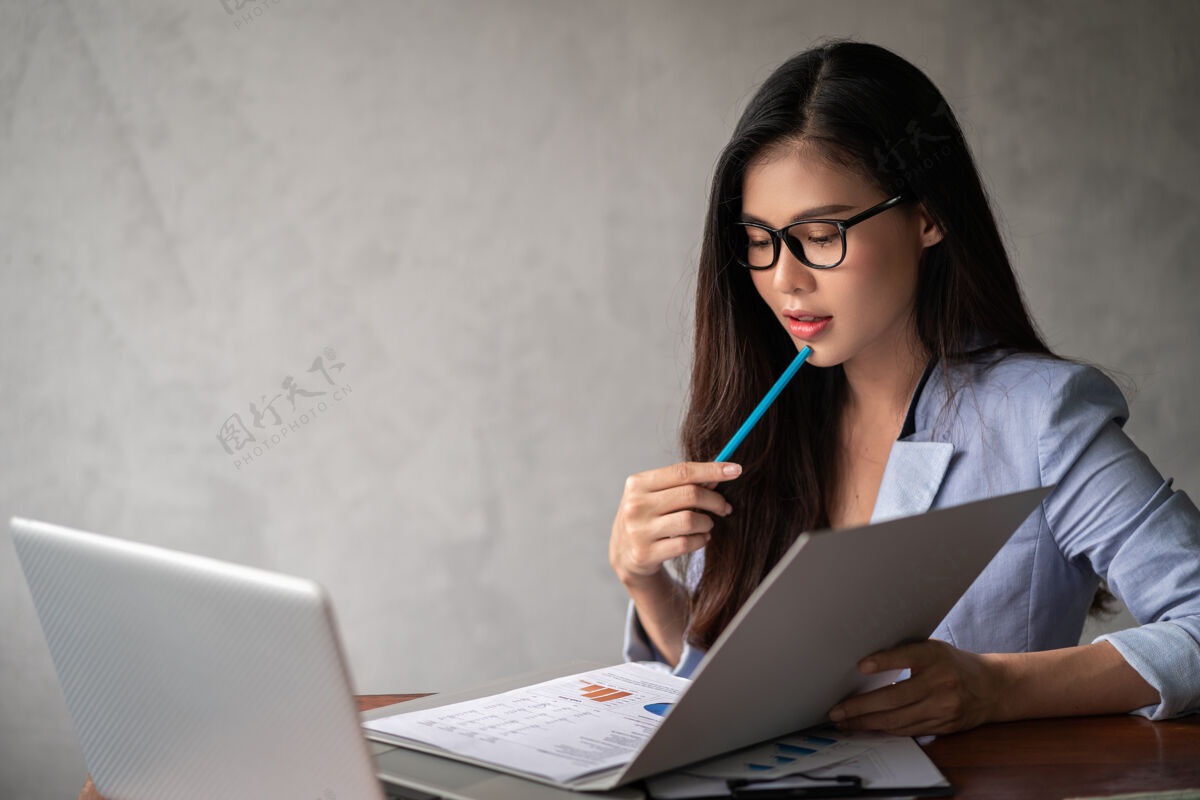 工人年轻快乐的亚洲女商人 穿着蓝色衬衫 在家工作 使用笔记本电脑 为自己的事业思考商业女性工作沟通