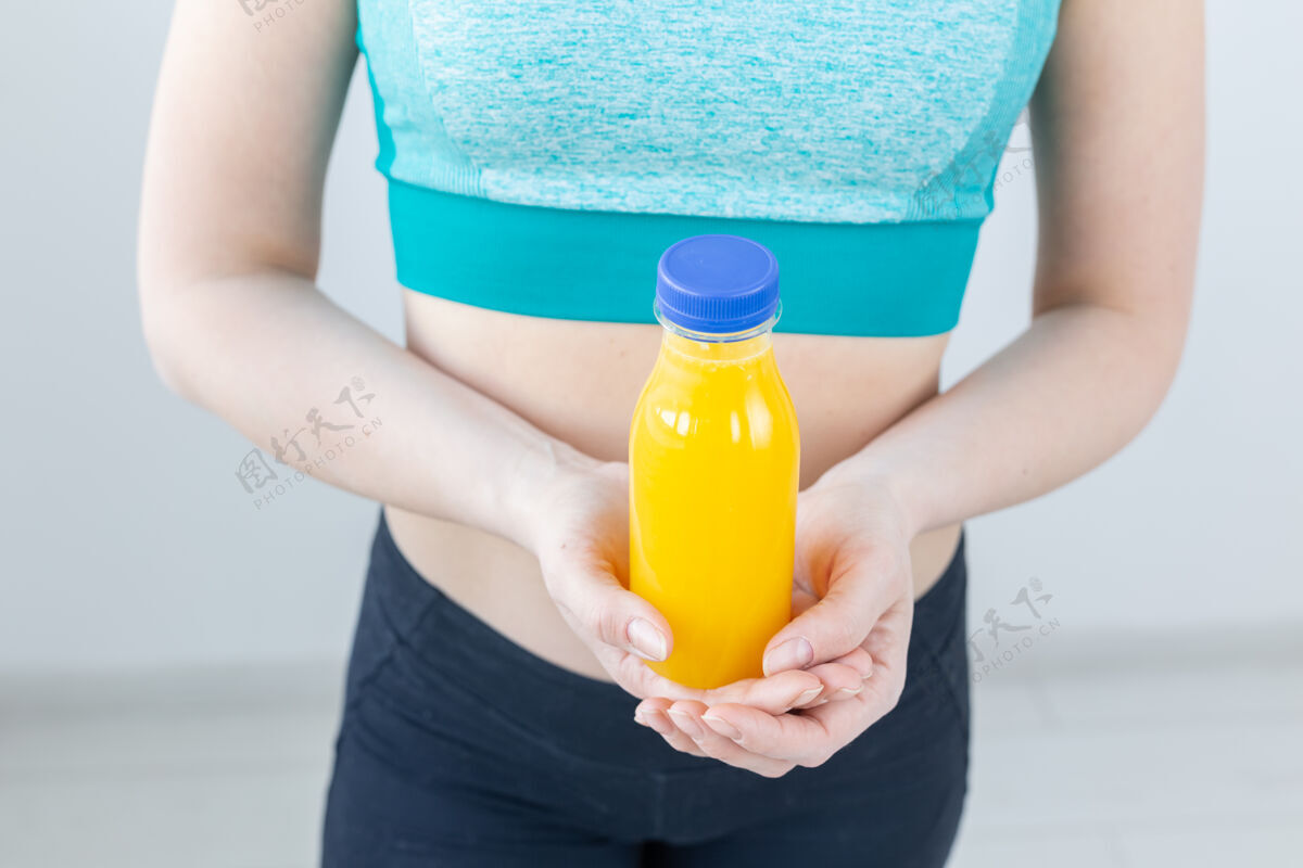 健身房特写镜头的健身妇女与果汁瓶身体体重女孩