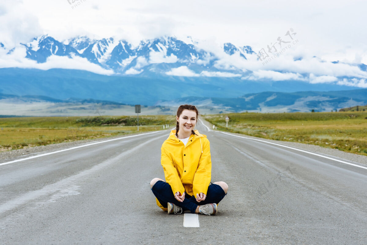 路快乐的女旅行者坐在路上 在山景里与她一起旅游度假自然女人年轻