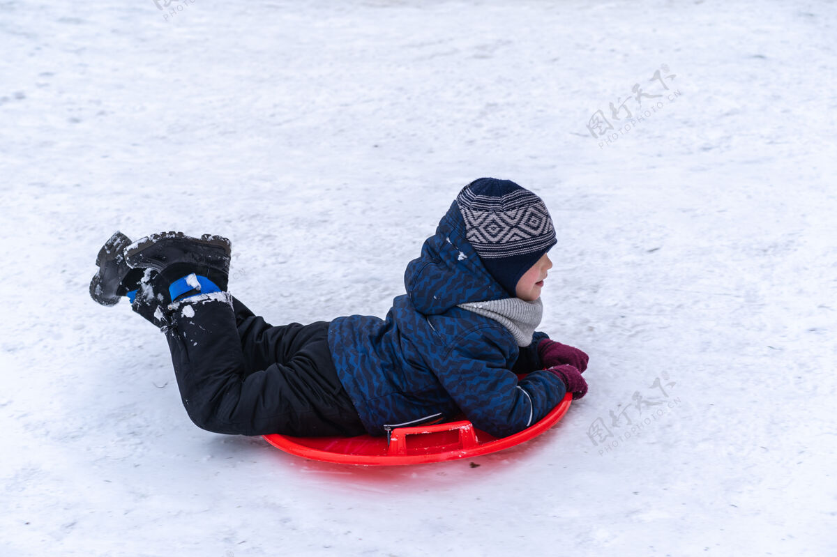 游戏一个小男孩在冬天骑雪橇幻灯片.winter假期雪橇天气滑梯